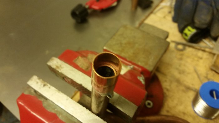 28mm kopparledning fastklämd i skruvstäd, med lödningstecken och verktyg i bakgrunden.