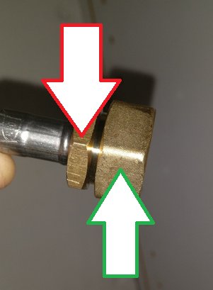 Röd pil visar var man ska hålla emot och grön pil pekar på locket som ska lossas på en röranslutning.