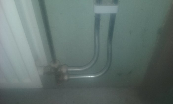 Rörinstallation med böjningar nära en termostat i ett pannrum, suddig bild.
