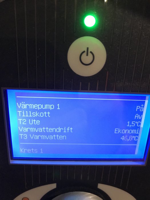 Display av en värmepumps kontrollpanel med temperaturvärden och statusindikatorer.