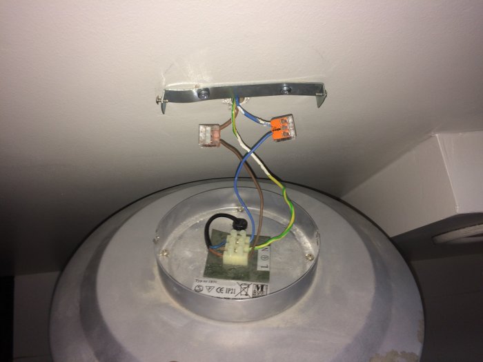 Elanslutning av taklampa med Wago-skruvplint i takkopp och synliga ledningar.