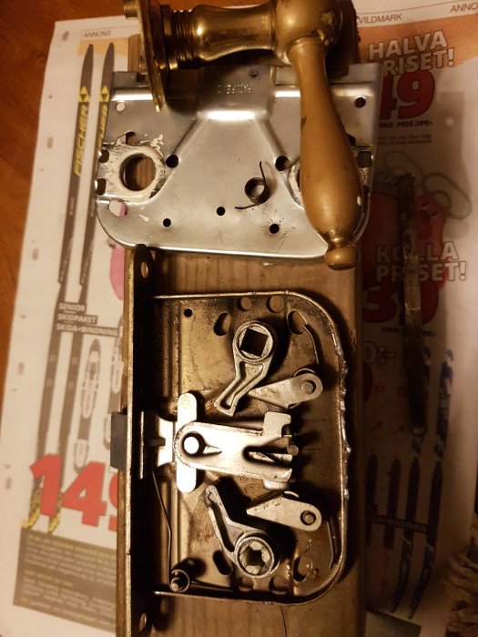 Uppdelat innedörslås från 80-talet på ett bord med synliga delar som vridklack och fjädrar.