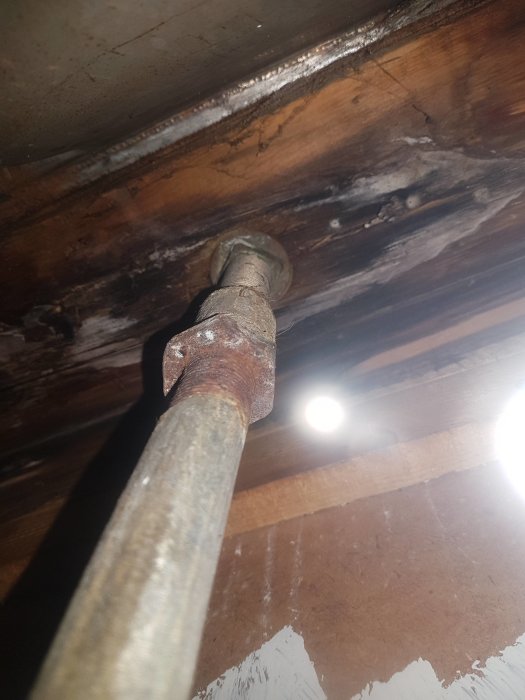 Gammalt stålrör i tak med klämringskoppling, potentiellt för byte inför renovering.