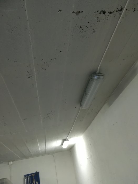 Garagetak med en lampa som lyser och en avstängd, smutsiga betongytor synliga.