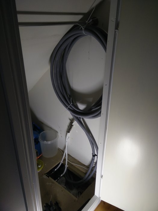 Rörinstallation i ett hörnskåp med flexslang ner på golvet och avstängningsventiler.