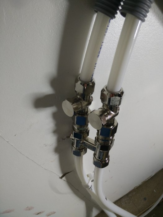 Nyinstallerade rör och avstängningsventiler på väggen, löst liggande på golvet för att undvika luftfickor.
