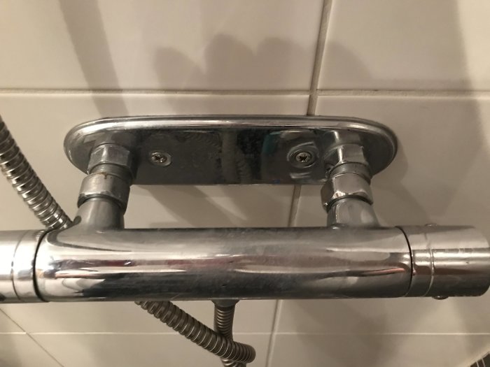 Kromad duschblandare med adaptern fast på väggfästet i badrummet.