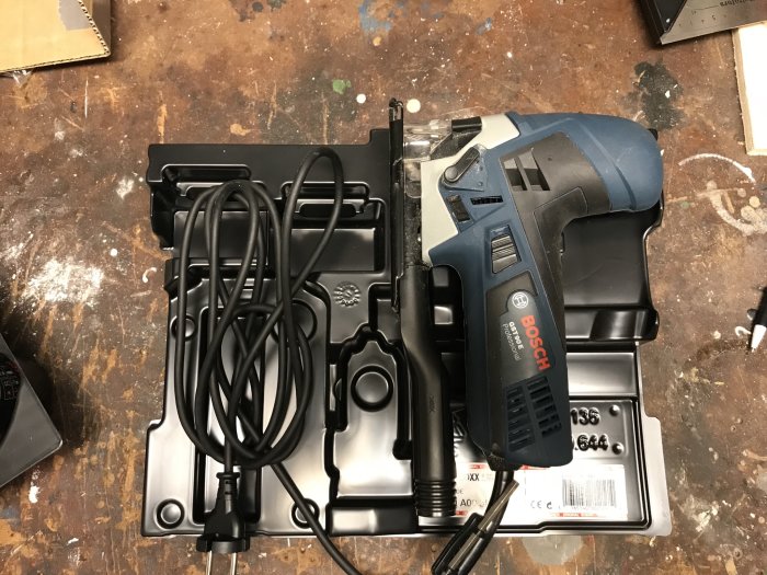 Bosch elverktyg med modifierad förvaringslåda, halva avlång del skuren bort, på arbetsbänk.