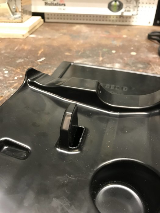 Modifierad svart plastdel med en halvskuren plupp.