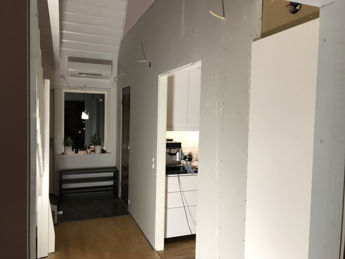 Nyinstallerade gipsväggar i ett hem under renovering med synliga lampkablar och undertak.