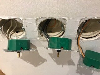 Tre elektriska dosor i en vägg, med synliga kablar och en grön installationsdosa.