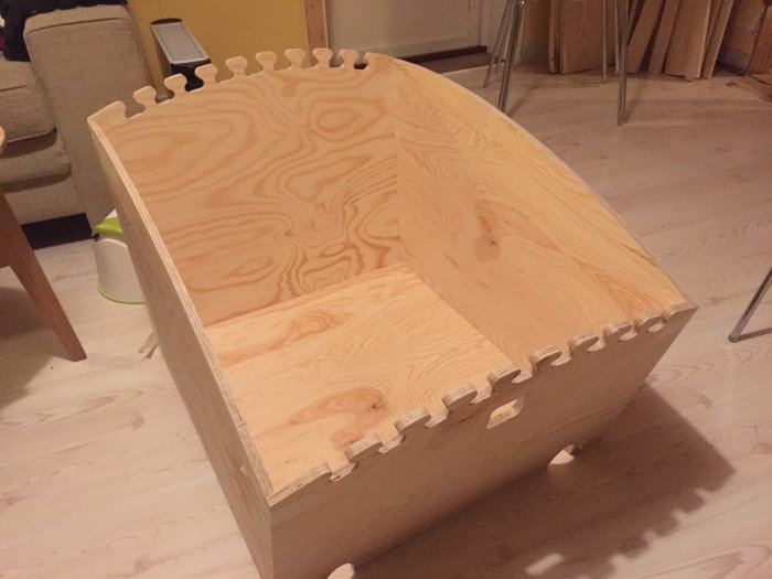 Halvfärdigt DIY byggprojekt av en träform med tandade kanter liknande ett pussel, på ett ljust golvet.