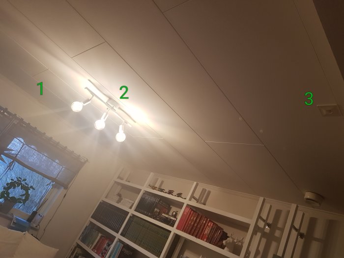 Rumsinteriör med taklampor markerade som 1 och 2 över vardagsrum och en markering som 3 för hallens lampa.