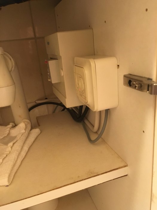 Eluttag och dosa inuti ett skåp, kopplat till golvvärmesystem, inför renovering.