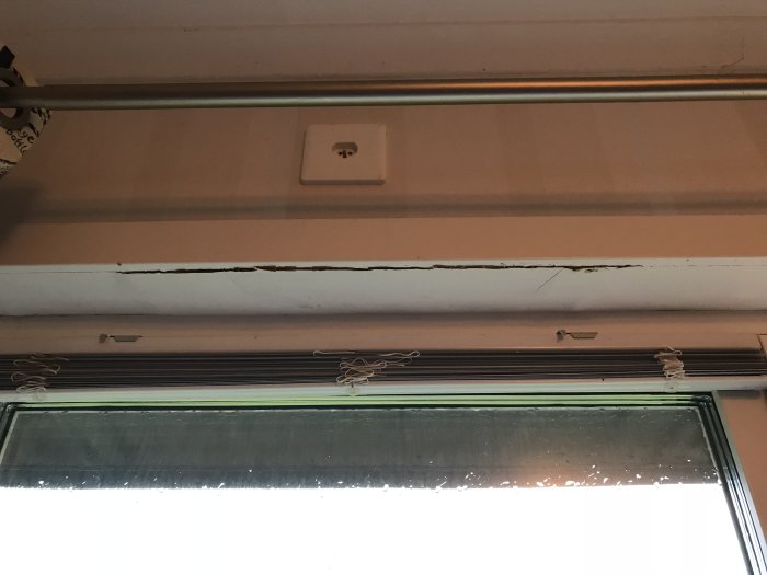 Skadad list över ett fönster med synliga sprickor och fuktskador innan renovering.