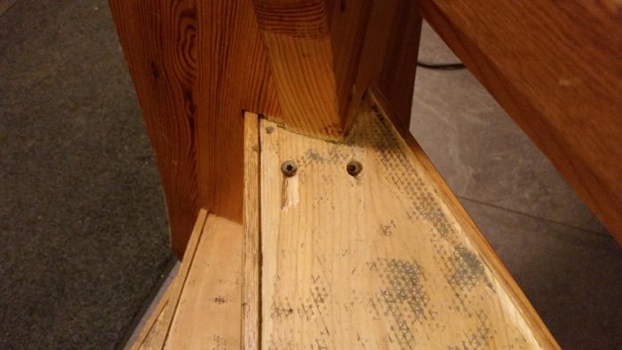 Trappehjørne med to nyligt tilføjede skruer i træet til venstre. Skruemærker og brug på trinene er synlige.