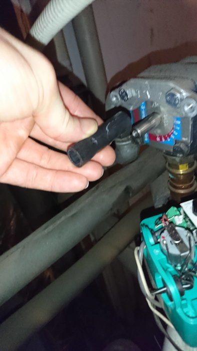 Hand känner på en shuntventil i en VVS-installation, med borttagen motor och synliga rör.