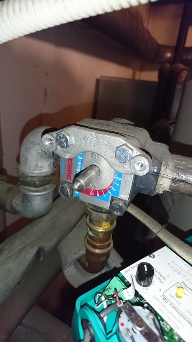 En hand som känner på en kärv ESBE shuntventil i ett VVS-system, med avlägsnad motor och verktyg synliga.