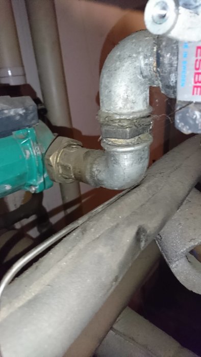 Rördelar nära en krök med en shunt och en delvis synlig temperaturmätare i ett värmeinstallationssystem.