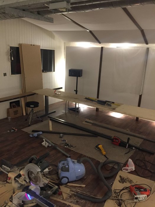 Renoveringsprojekt med stålprofiler längs en träskiva, verktyg och byggmaterial på golvet.