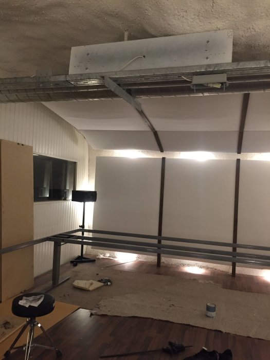 Målad stålbjälke installerad i ett rum under konstruktion, med verktyg och målardosa på golvet.