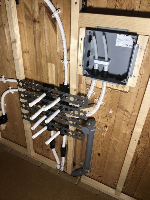 Nyinstallerade rör och en inbyggnadsbox för tappvatten fastmonterade på en trävägg.