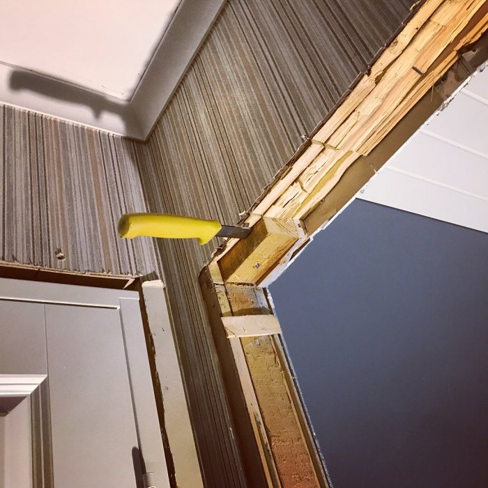 Delvis installerad dörr med synlig träregel och valv i en byggnad under renovering.