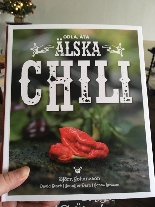 Hand håller boken "Älska Chili" med bilde på en röd chili.