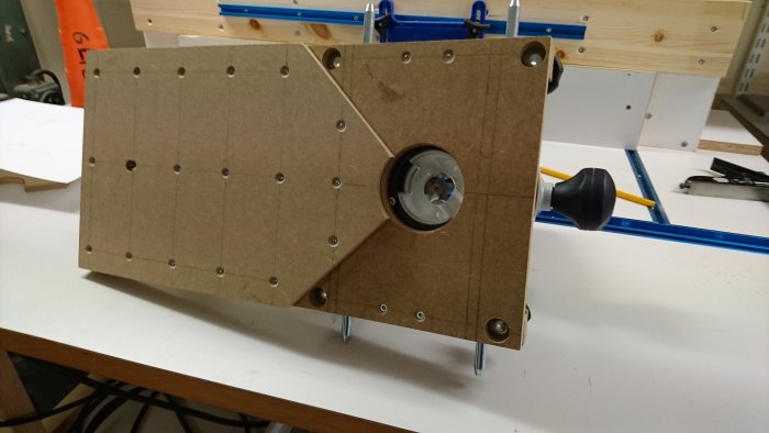 Hemmagjord fräsrigg för kantlister med MDF-sula och fräsinsats på arbetsbänk.