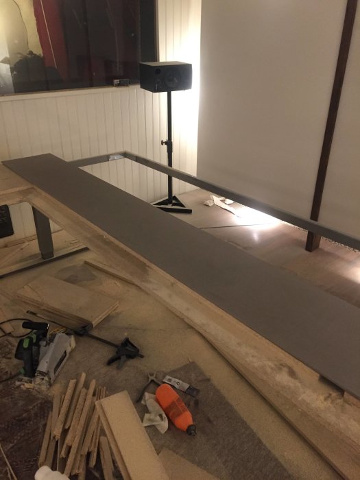 Ljusgrå Valchromat-skiva på uppkantade arbetsbänkar med verktyg och byggmaterial runtomkring.