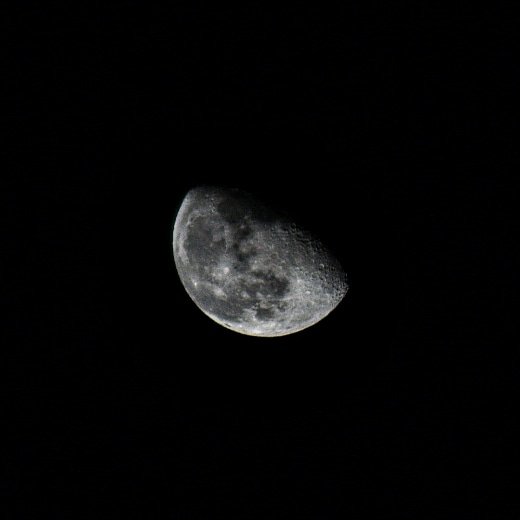 Halvmåne i närbild mot en mörk himmel, inga stjärnor synliga.