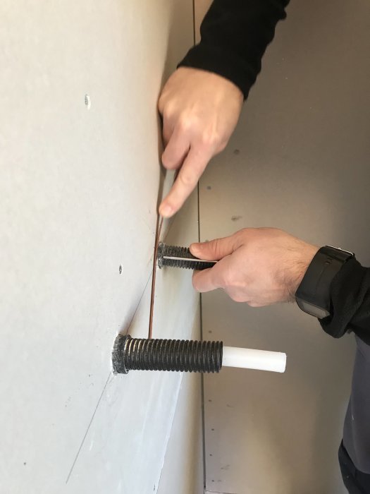 Person monterar isoleringsskiva på vägg med hjälp av speciellt monteringsverktyg.