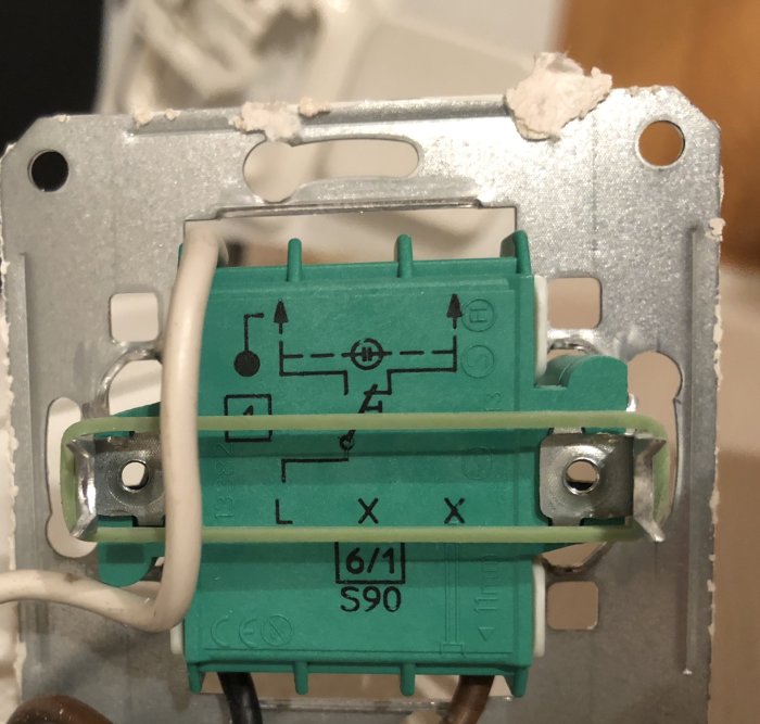 Gammal väggströmbrytare öppnad med synliga kablar och anslutningar, redo för byte till dimmer.