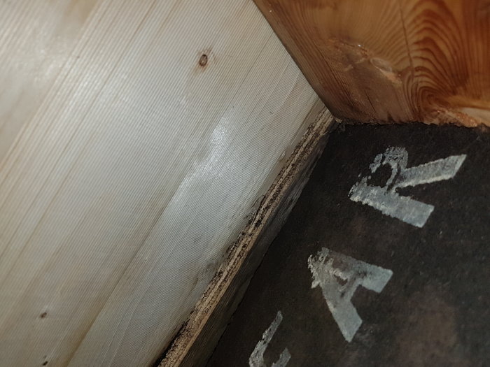 Närbild på blöt gammal papp under takfönsterkupa med ny papp vikt undan.