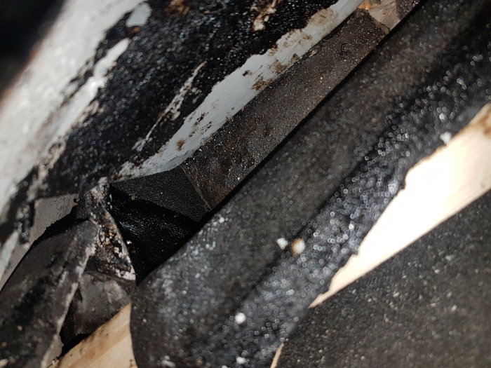 Närbild på en fuktig råspont och takpapp under en fönsterkupa på taket med synliga kondensdroppar.