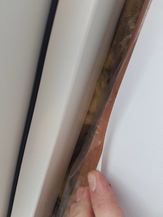 Närbild på en fönsterkant med misstänkt kondens och blött område mellan ny och gammal takpapp.