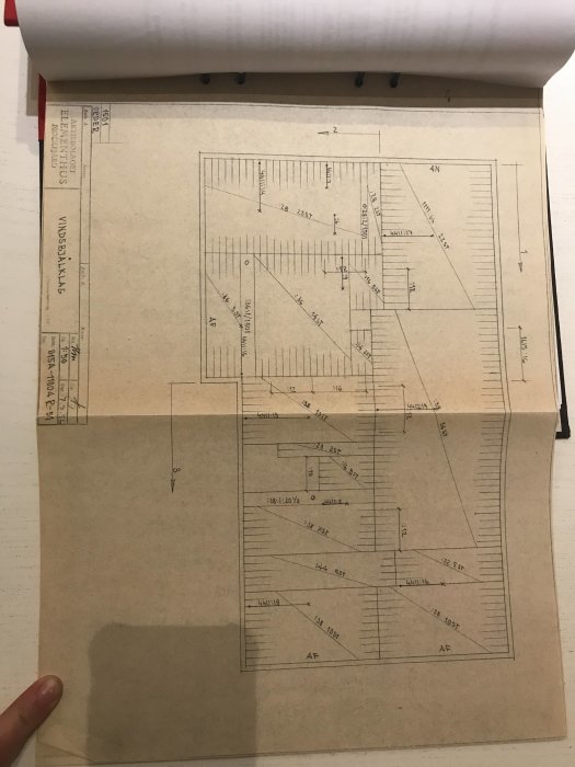 Arkitektritning av en byggnad utbredd på ett bord med mått och anmärkningar synliga.