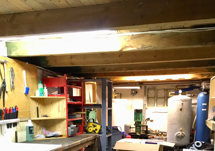 Takbjälkar i pannrum med lågt i tak, arbetsbänk och diverse verktyg.