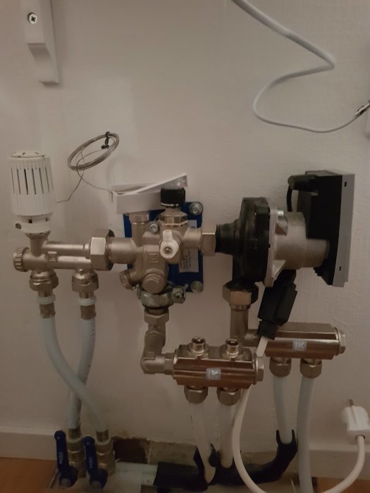 VVS-installation med termostatventil, pump och rörledningar i ett hushåll.