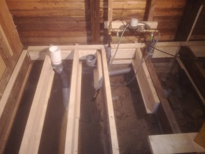Renovering av badrum med synlig torpargrund, bjälklag och avloppsrör under konstruktion.