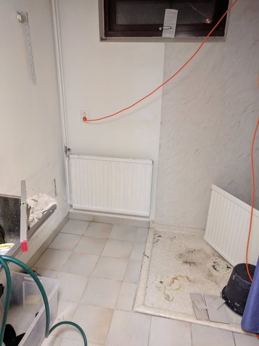 Värmeelement kopplat med vridna anslutningsrör vid 90 grader i ett ofärdigt rum med kakelgolv.