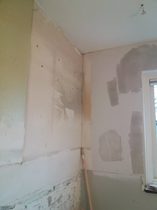En ojämnt spacklad hörnvägg i ett renoveringsprojekt med synliga lufthål och fläckar efter bredspackling.