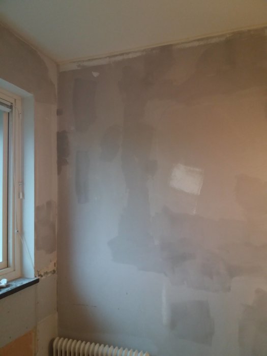 Renoverat kök med rörig bredspackling och synliga lufthål på en kaotiskt spacklad vägg.