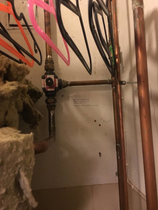 VVS-installation med kopparrör och avstängningsventil i ett skåp, isolering syns till vänster.