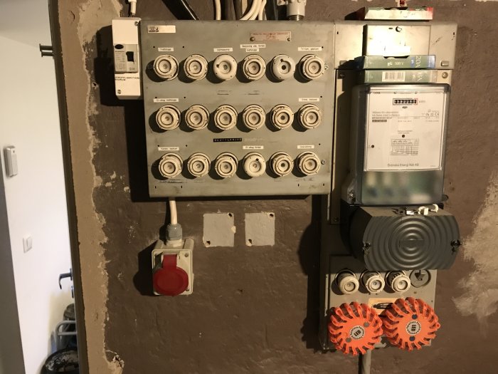 Äldre elcentral med skruvsäkringar och en energimätare i ett hus från 1900-talets början.