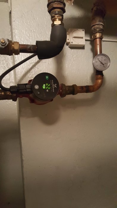 Värmesystem med en cirkulationspump och ett tryckmätare som visar nära noll i en källare.
