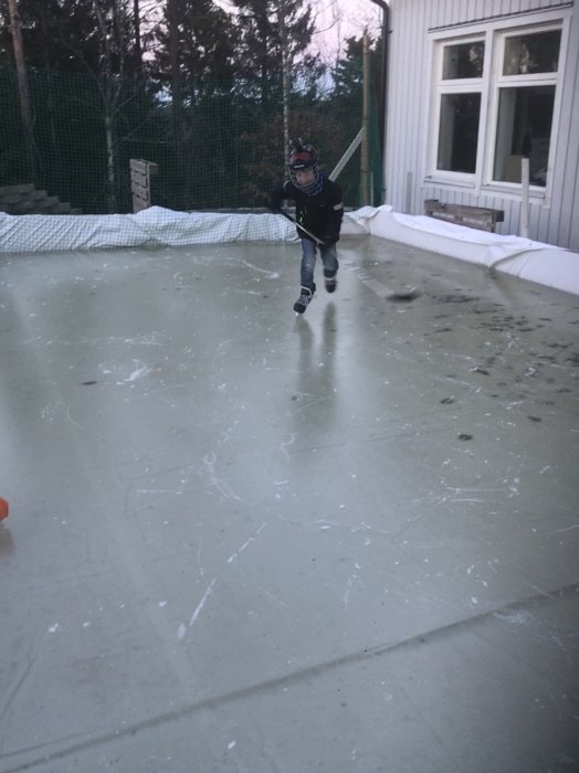 Barn spelar hockey på hemmagjord isrink i trädgården.