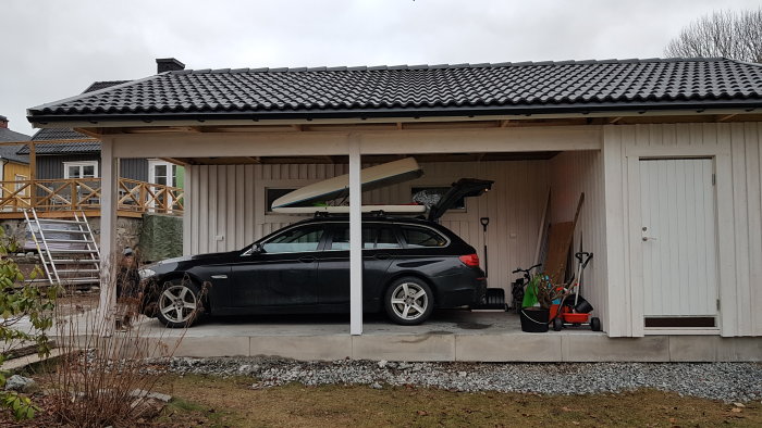 Familjebil med taklåda parkerad under carport med högt tak och marginal över.