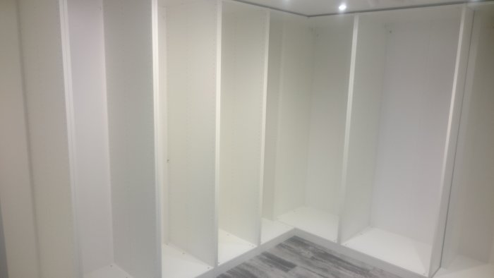 Tom garderob utan inredning i ett nyligen renoverat källarutrymme.