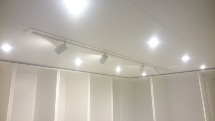 Renoverad källarkorridor med inbyggda garderober och modern takbelysning.